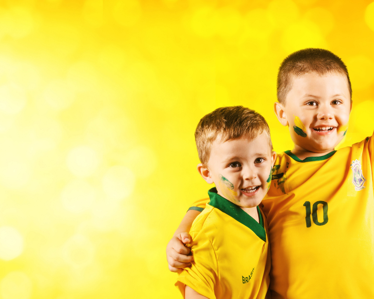 Два маленьких мальчика в спортивной форме на желтом фоне