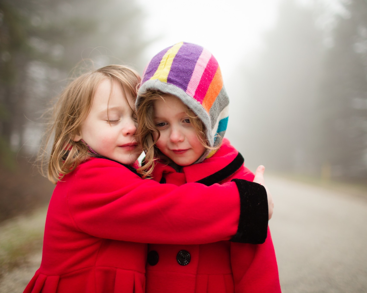 Две маленькие девочки обнимают друг друга 