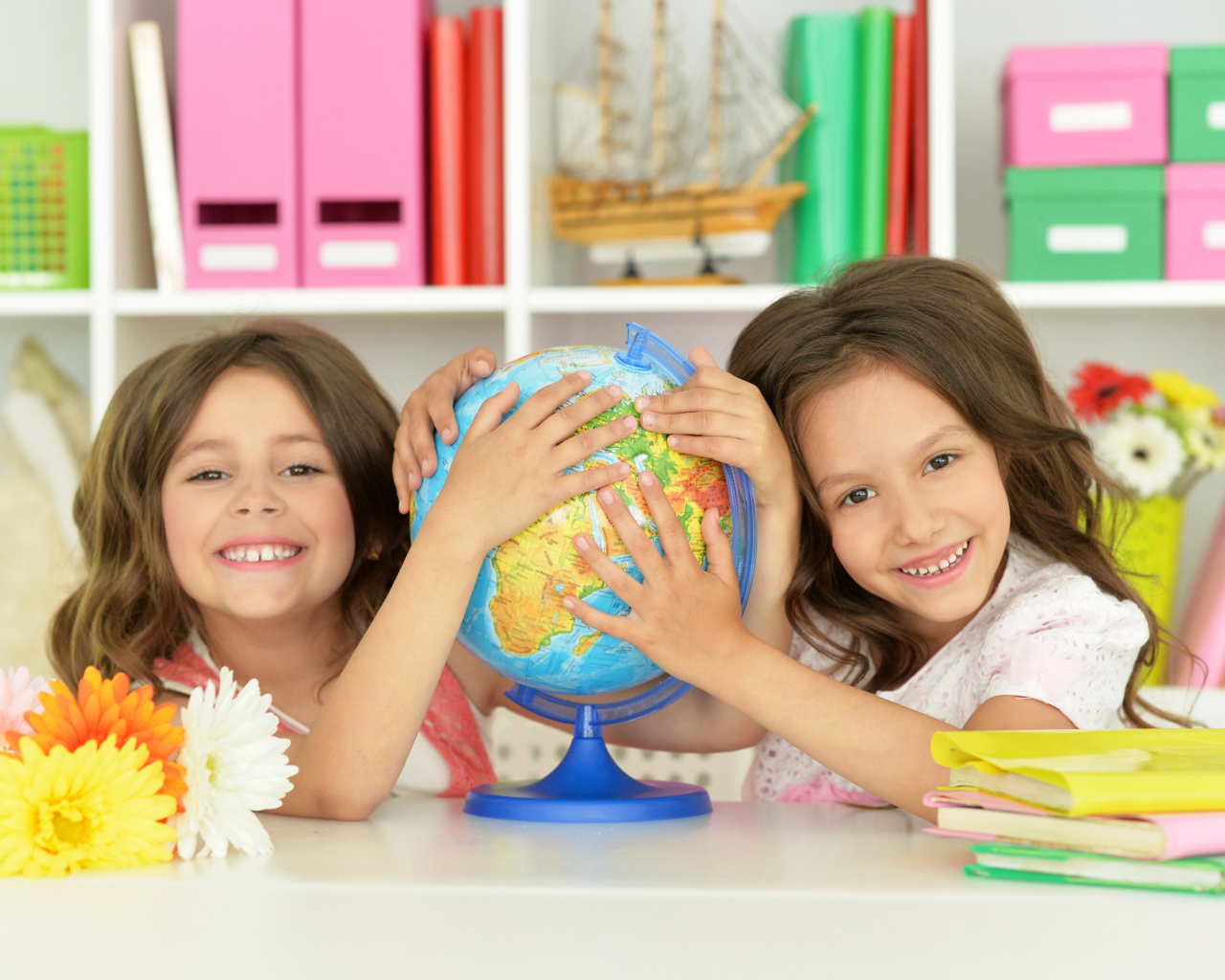 Две маленькие девочки школьницы с глобусом  в руках