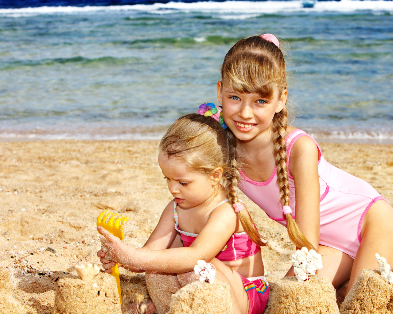 Две маленькие девочки гуляю на песке на пляже 