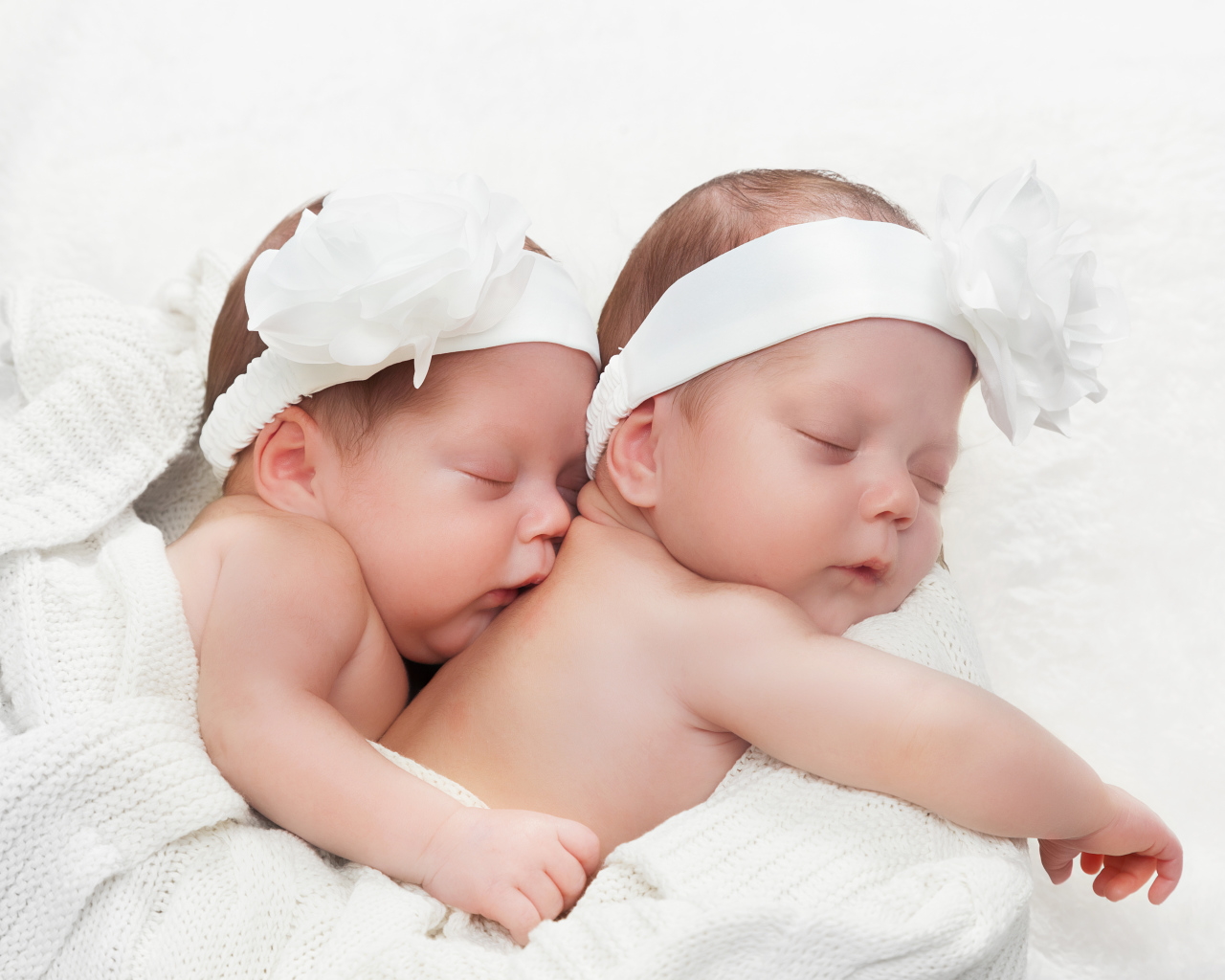 Два спящих младенца с большими белыми цветами на голове