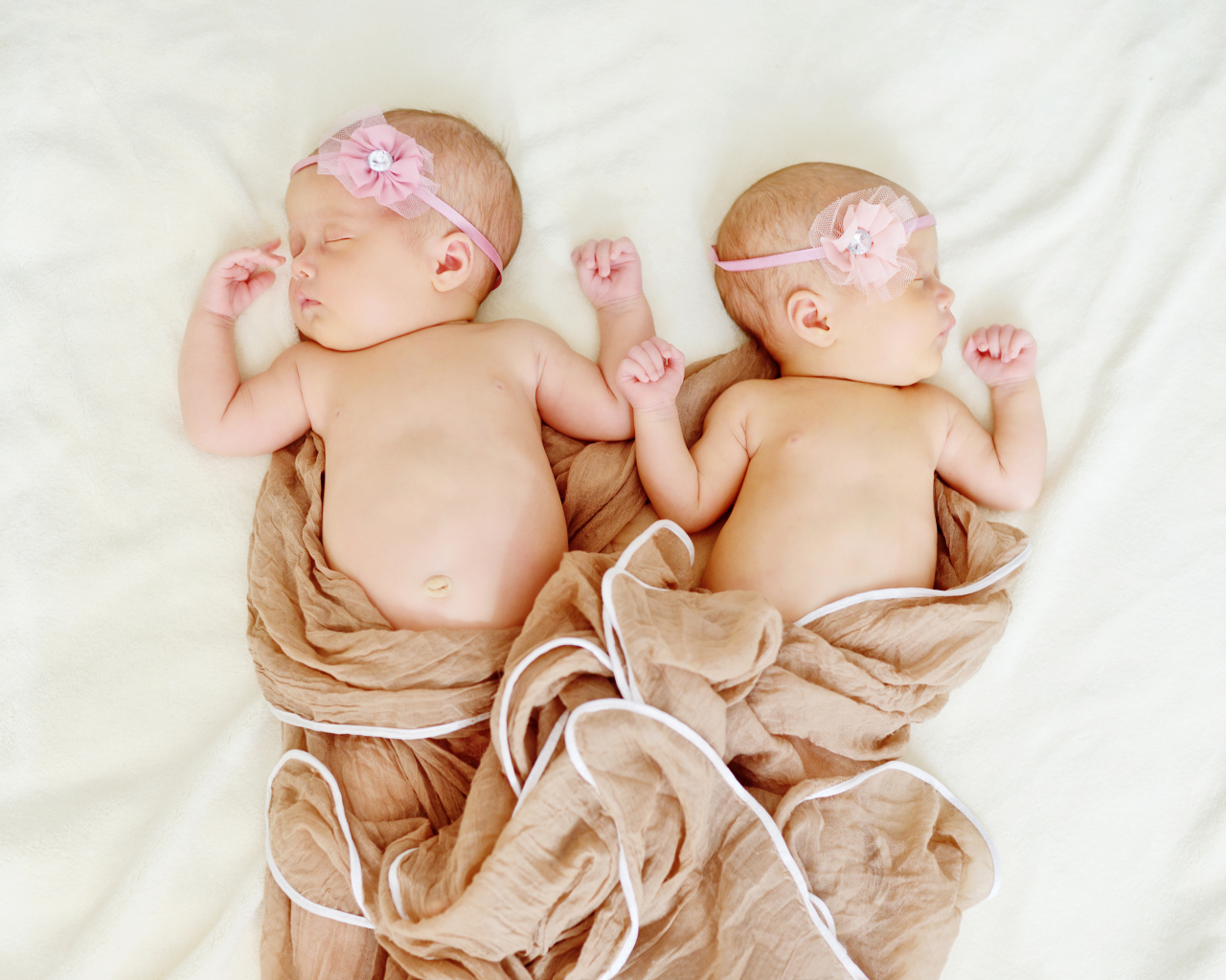 Два спящих младенца с розовыми цветами на голове