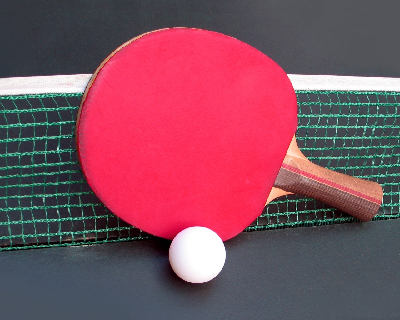 Красная ракетка для настольного тенниса у сетки 