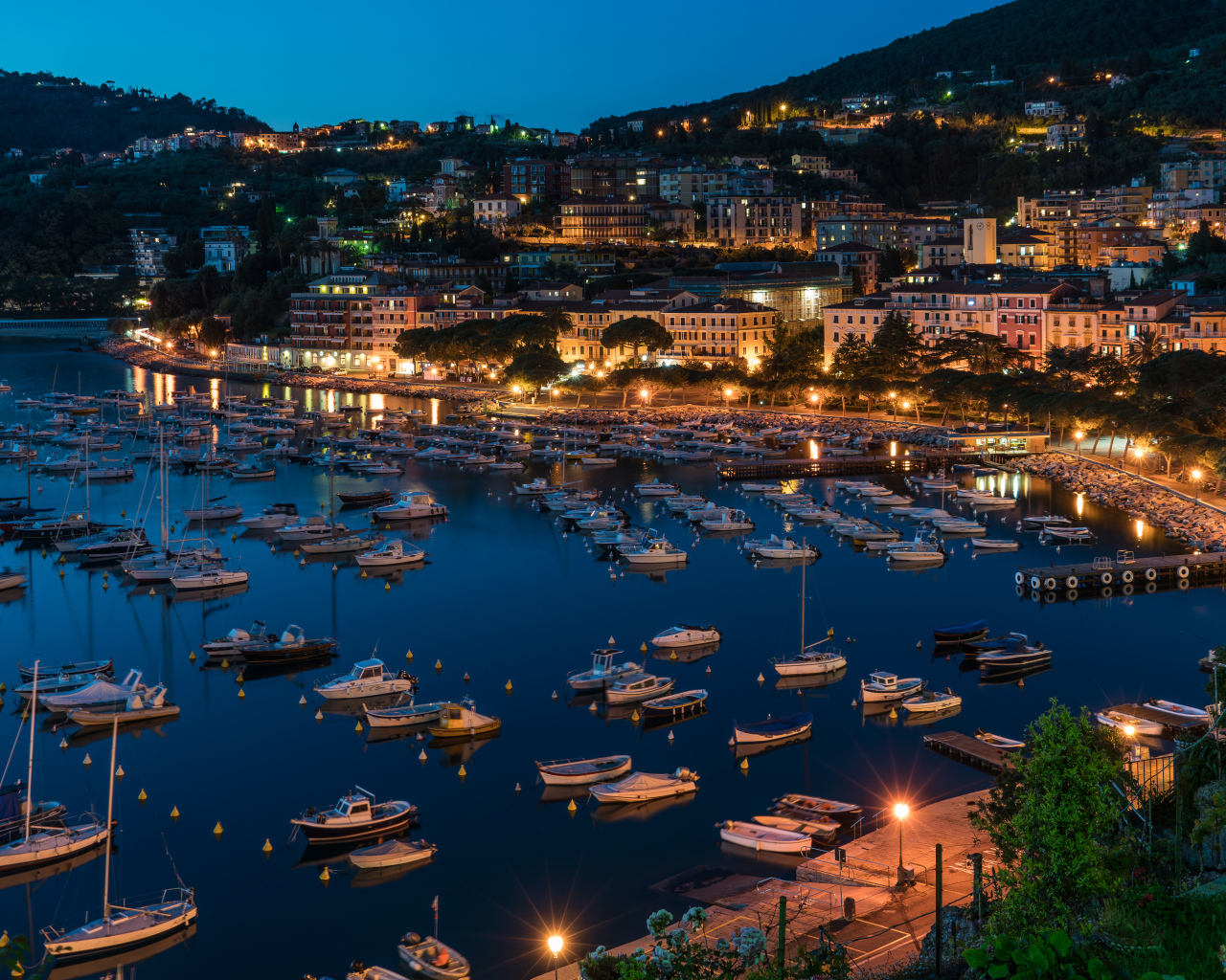 Панорама ночного города и лодки на причале у побережья, Лигурия. Италия