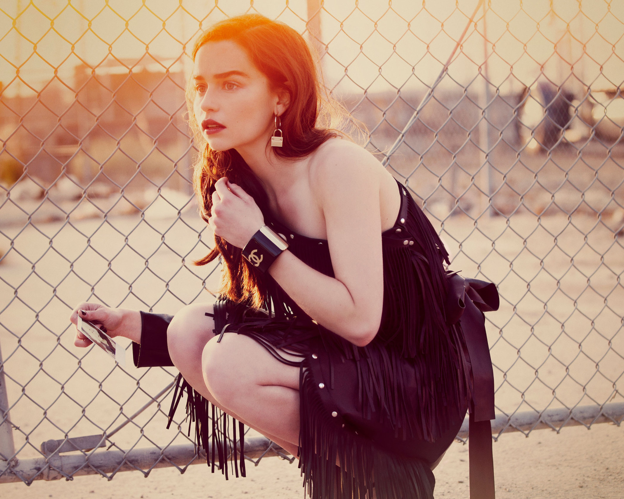 Актриса Эмилия Кларк в красивом черном платье в лучах солнца