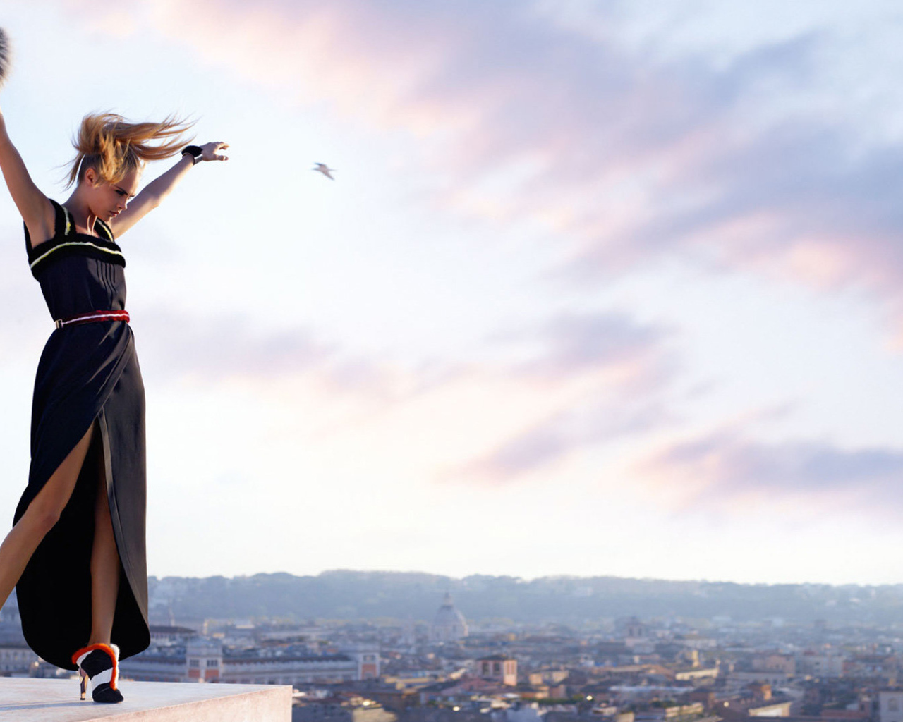 Актриса Кара Делевинь в черном платье на фоне неба 