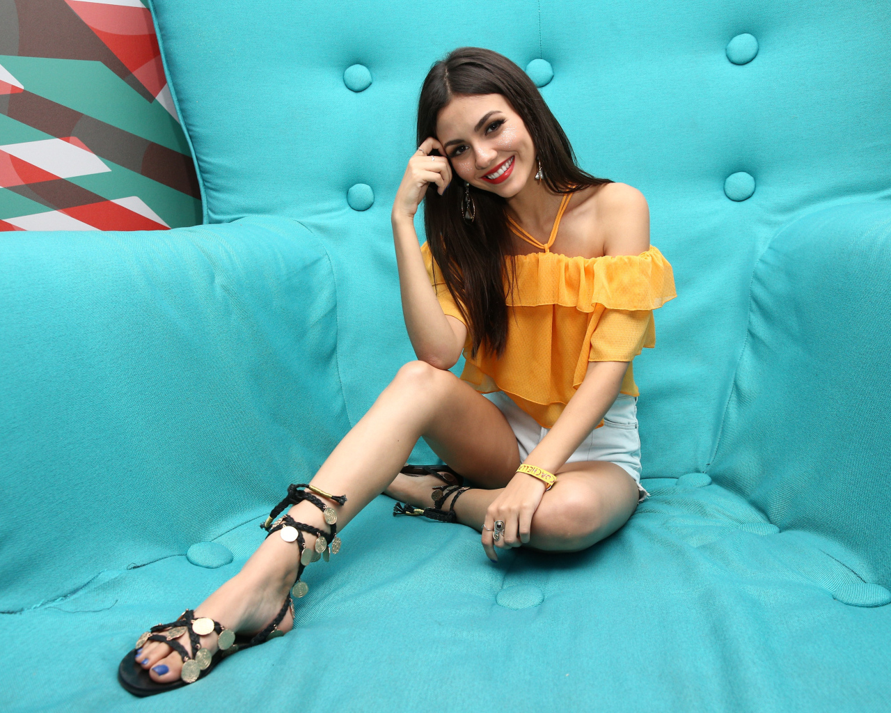 Актриса брюнетка Виктория Джастис сидит на синем диване 