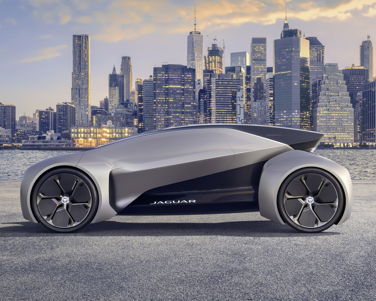 Серебристый электрический автомобиль  Jaguar Future-Type на фоне небоскребов