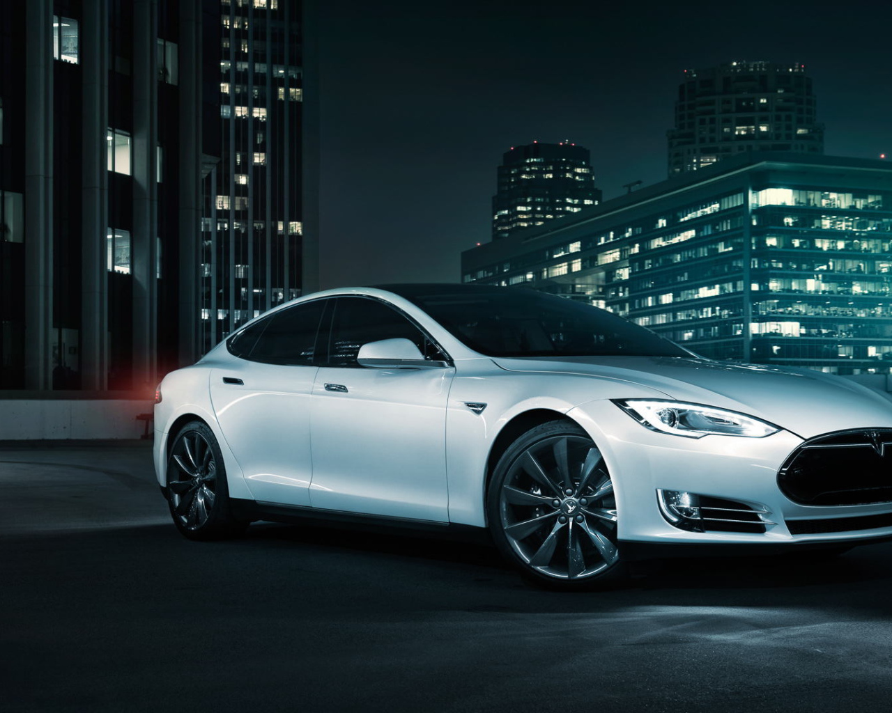 Белый электромобиль Тесла на фоне города 
