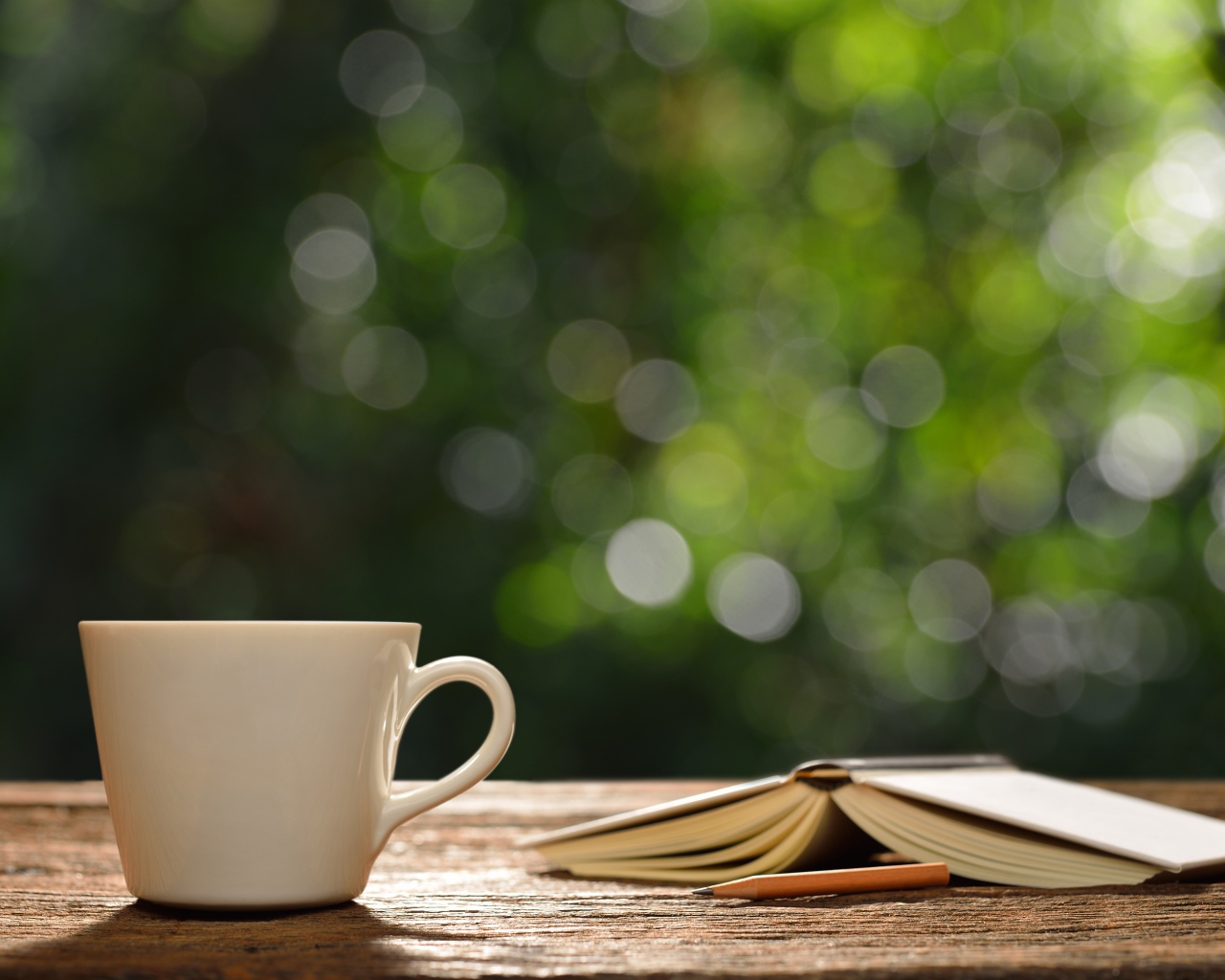 Белая чашка на столе с открытой книгой