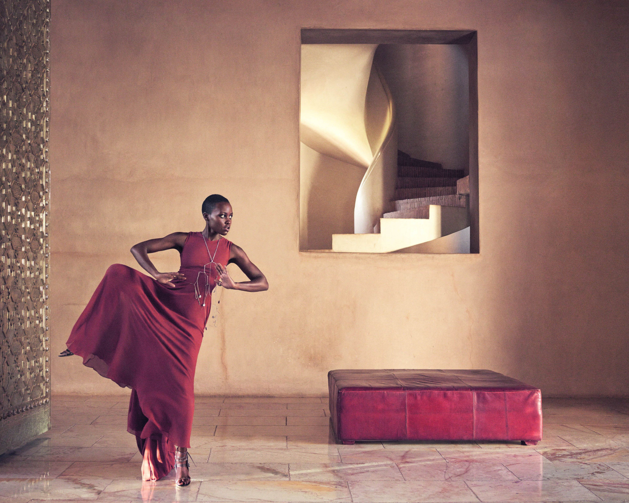 Молодая актриса Люпита Нионго танцует в красном платье