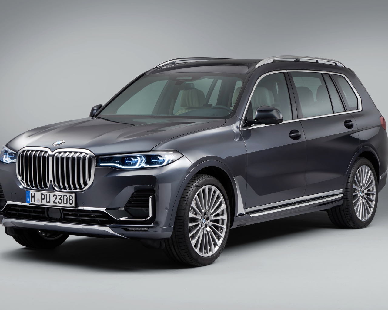 Серебристый внедорожник BMW X7, 2018 года на сером фоне