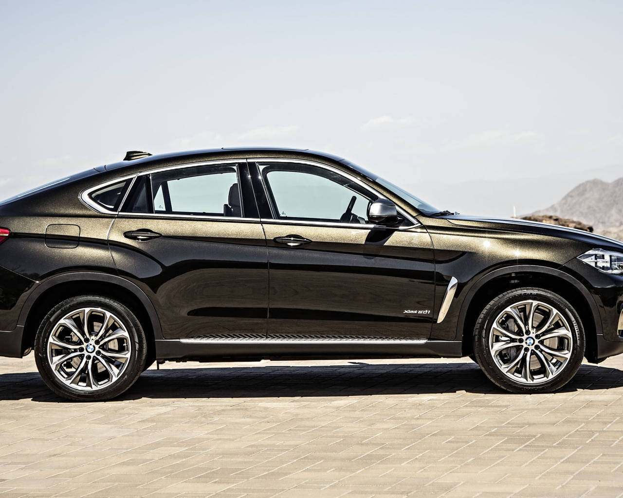 Черный автомобиль BMW X6, 2018 года вид сбоку