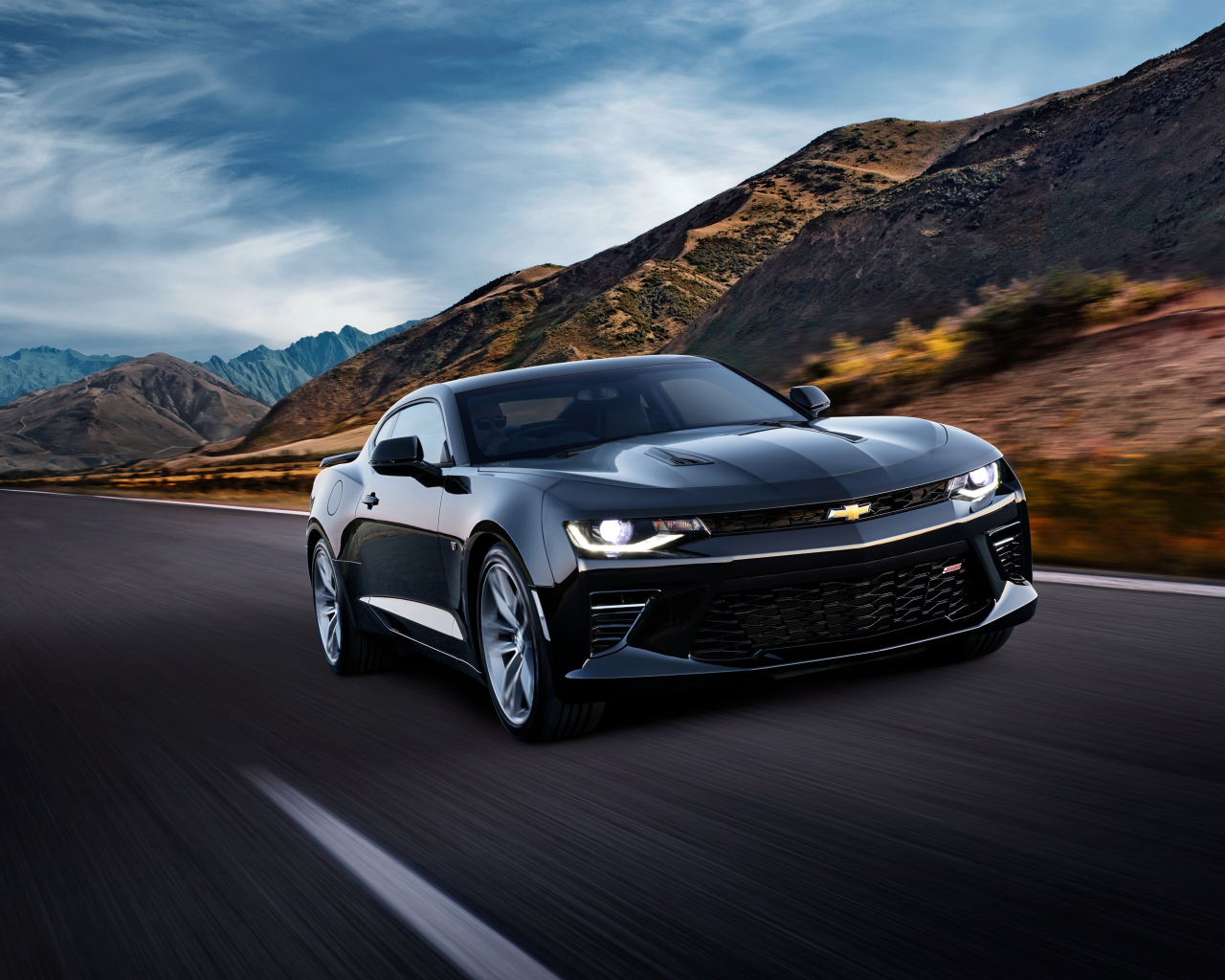 Черный быстрый автомобиль Chevrolet Camaro SS, 2018 года на трассе у гор
