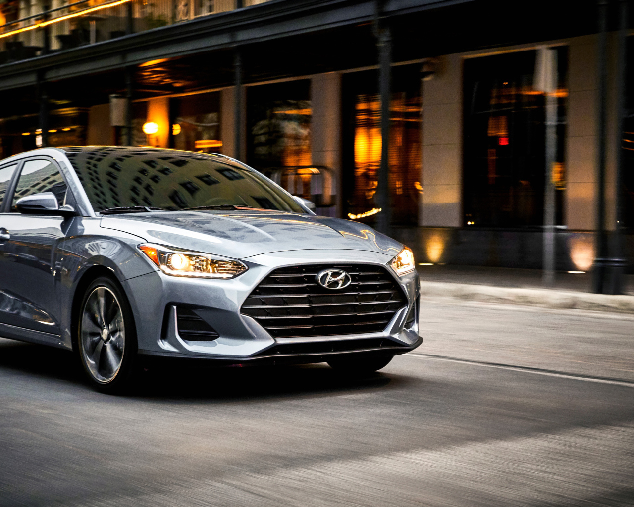 Серебристый автомобиль Hyundai Veloster, 2019 с  включенными фарами 