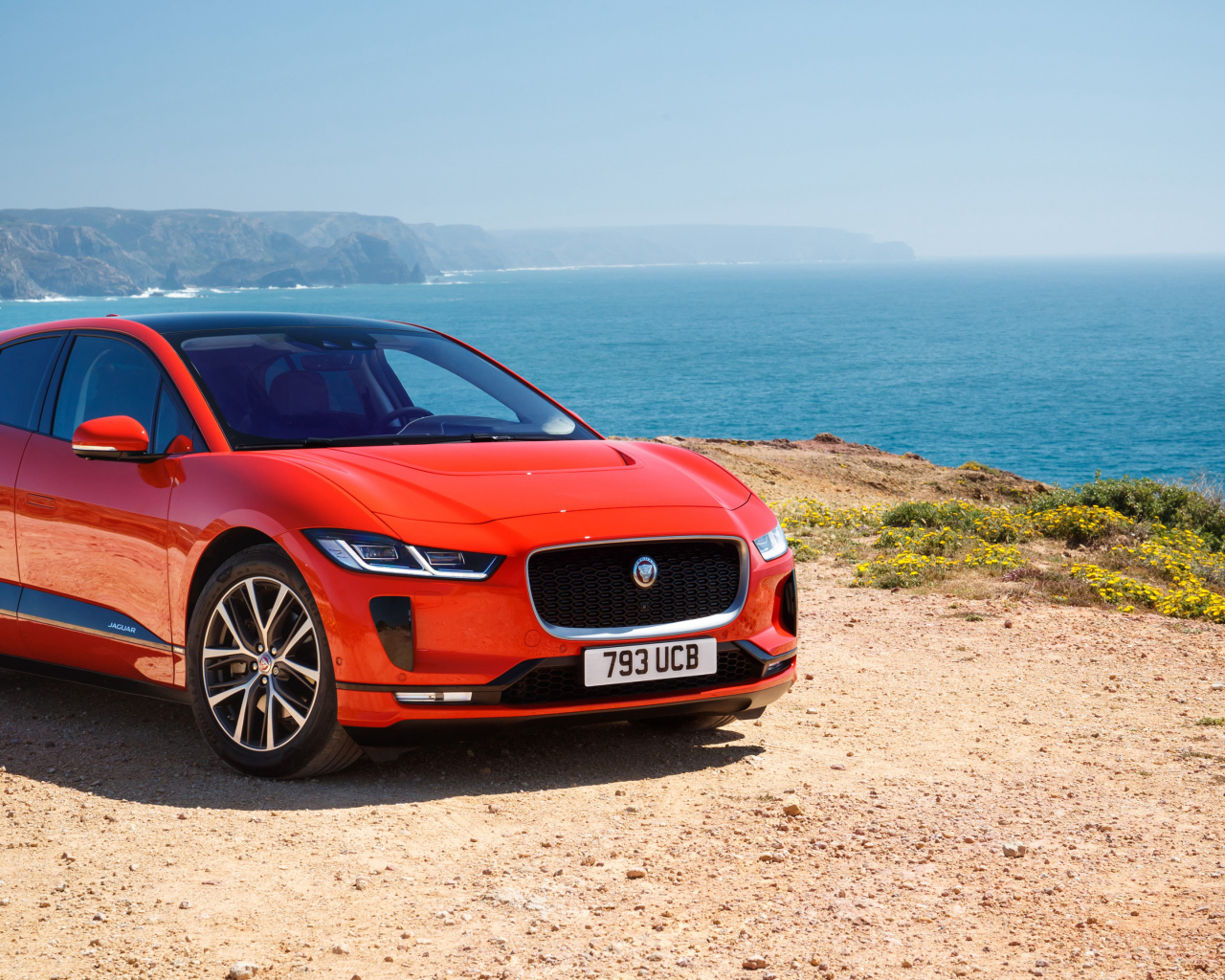 Красный Jaguar I-Pace EV400 AWD HSE First Edition 2018 года на фоне океана 