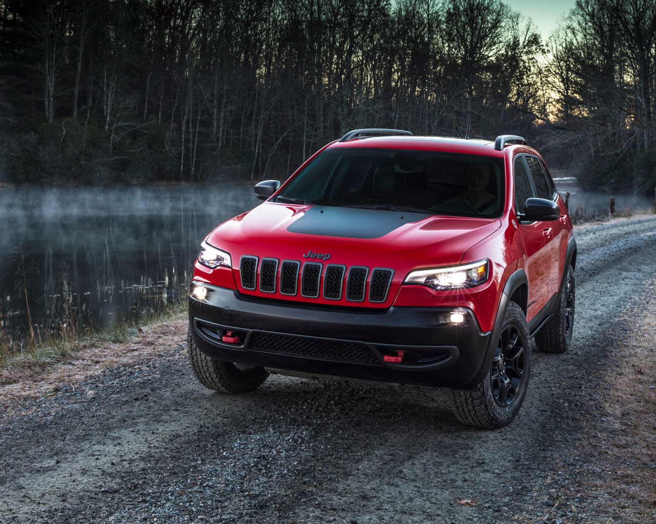 Красный автомобиль Jeep Cherokee Trailhawk, 2019 на дороге у реки