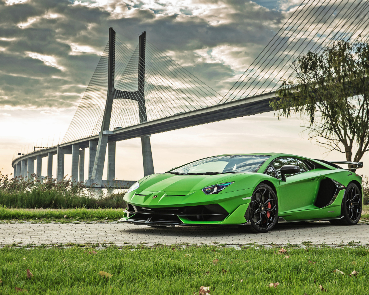 Зеленый дорогой автомобиль Lamborghini Aventador SVJ 2018 года на фоне моста