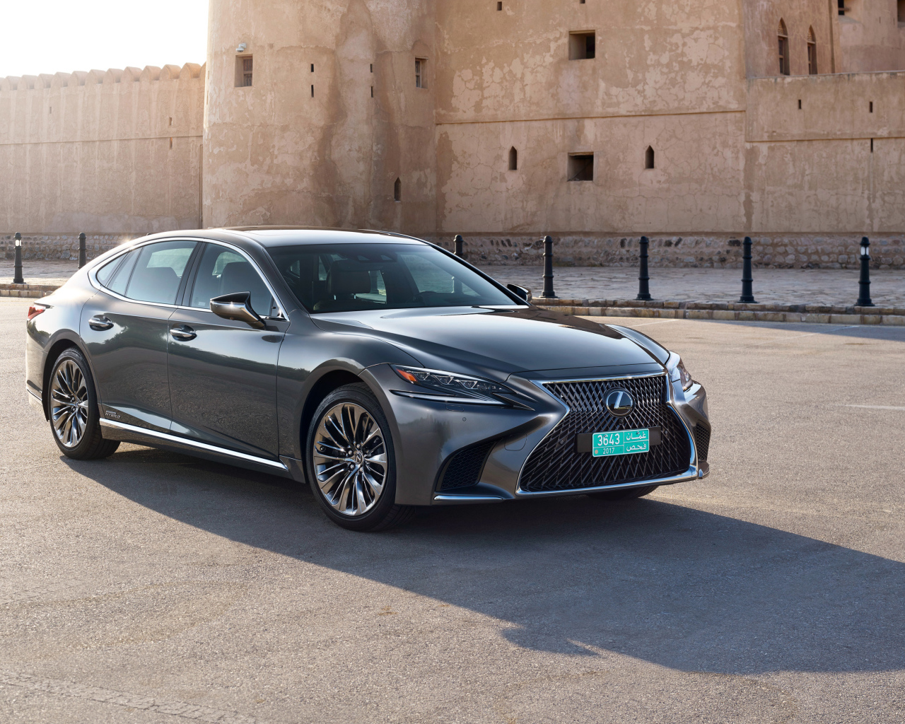 Стильный автомобиль Lexus LS 500h AWD, 2018 на фоне крепости