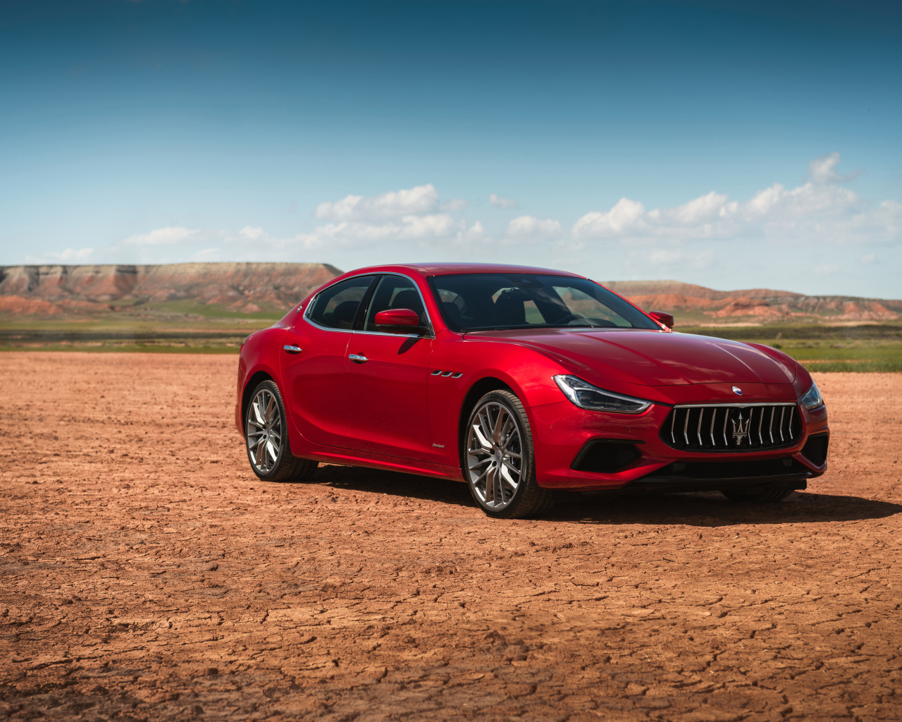 Красный автомобиль Maserati Ghibli на фоне голубого неба