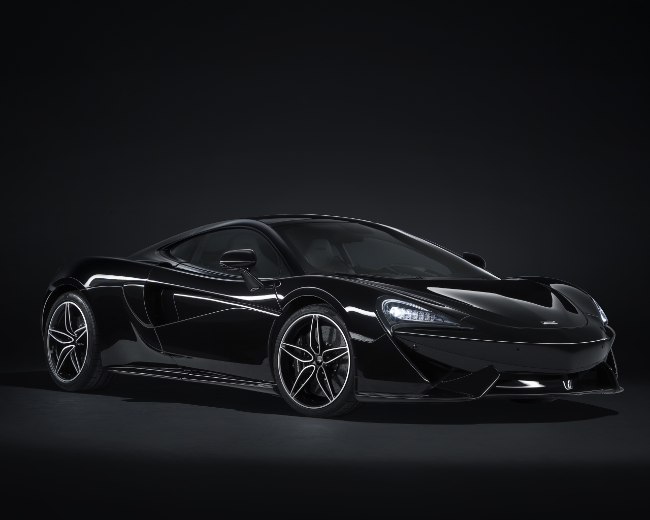Черный автомобиль McLaren 570GT на сером фоне