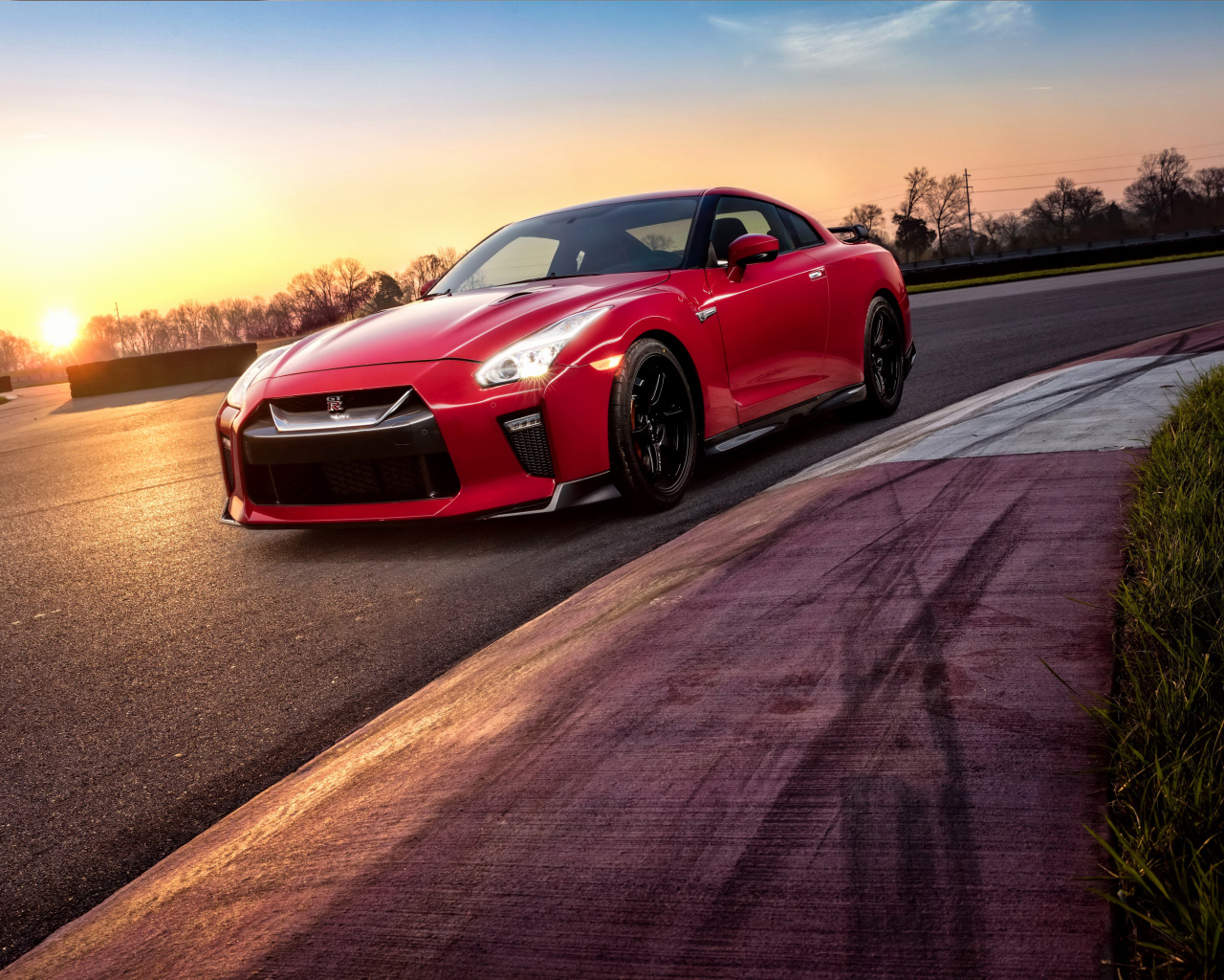 Красный автомобиль Nissan GT-R 2018 года на трассе на закате