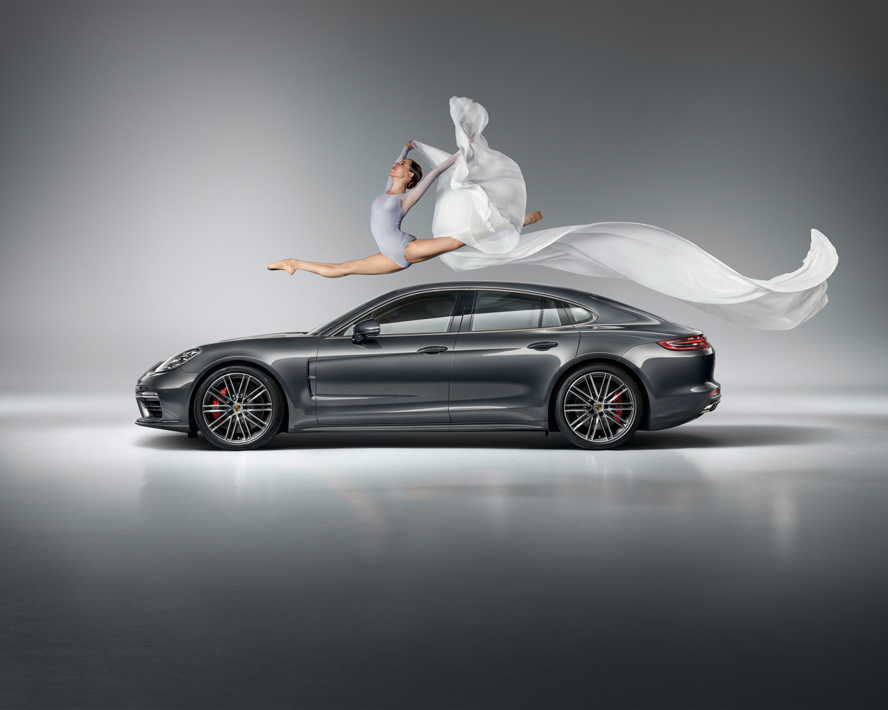 Фантастический прыжок гимнастки через серебристый автомобиль  Porsche Panamera Turbo