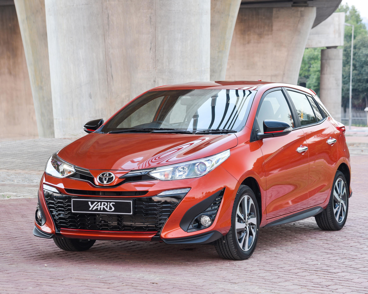 Красный автомобиль Toyota Yaris под мостом 