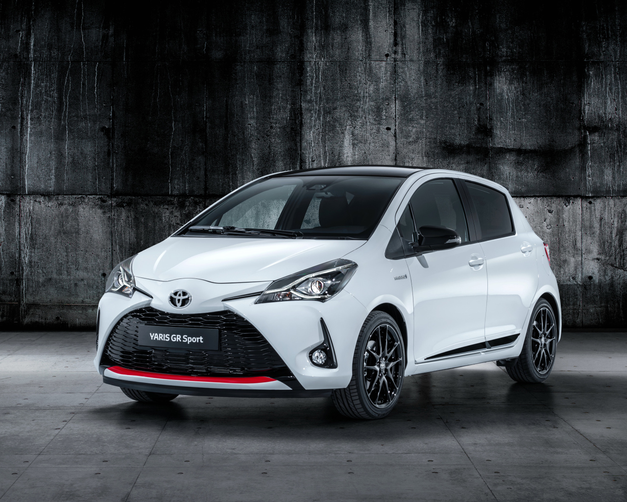 Белый автомобиль Toyota Yaris на сером фоне 