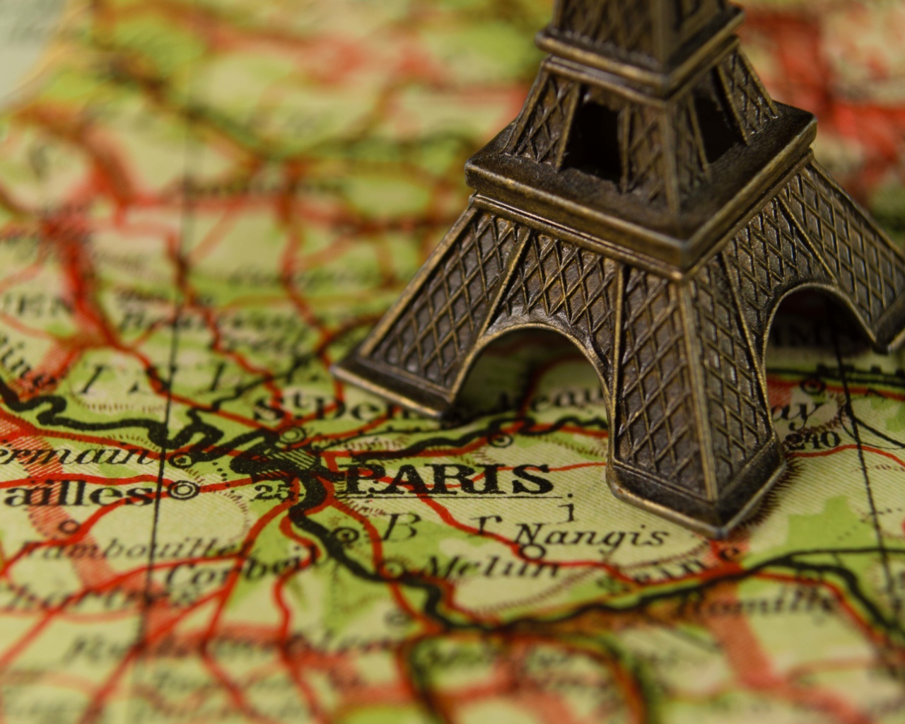 Маленькая статуэтка Эйфелева башня стоит на карте