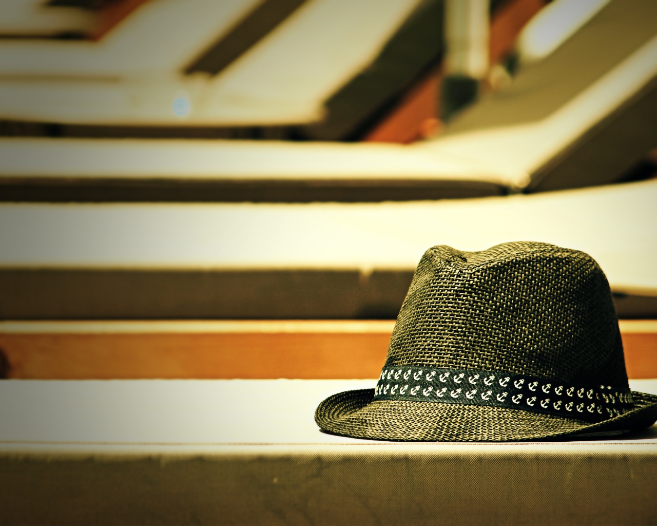 Летняя шляпа лежит на лавке в лучах солнца
