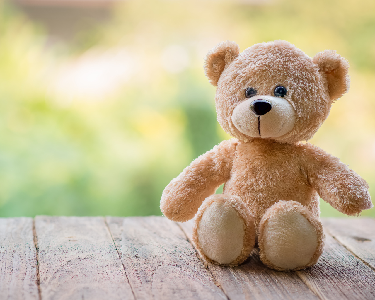 Плюшевый медведь сидит на деревянных досках