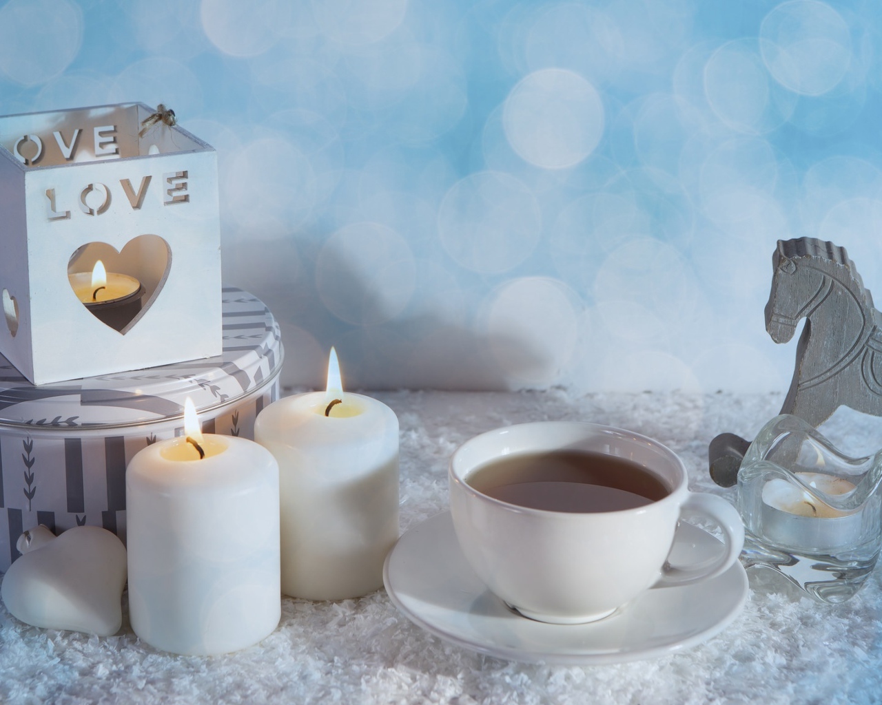 Свечи, чашка чая и фигура лошади на столе 