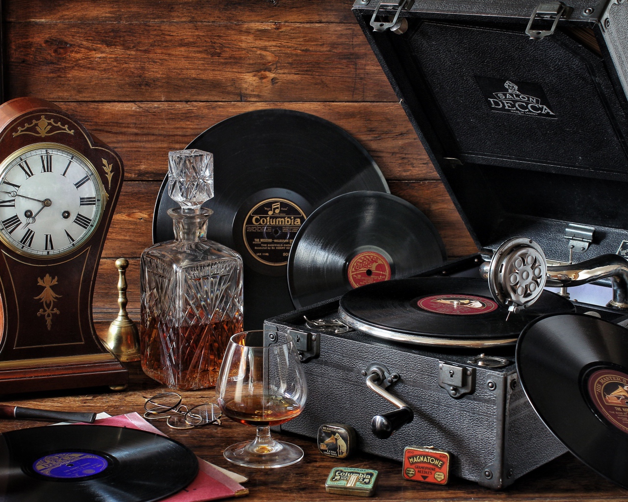 Старый граммофон с виниловыми пластинками, часами и коньяком на столе