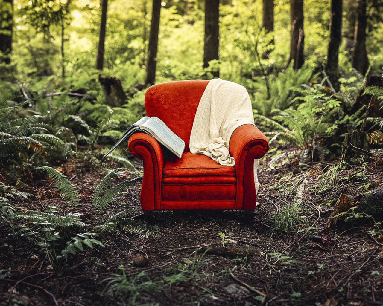 Старое красное кресло с книгой и пледом в лесу 