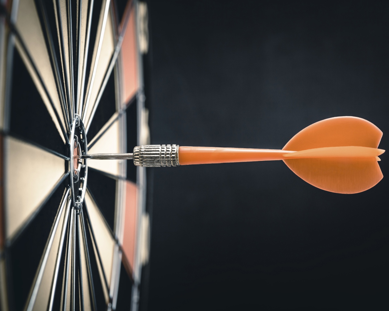 Оранжевый дротик в доске для дартса 