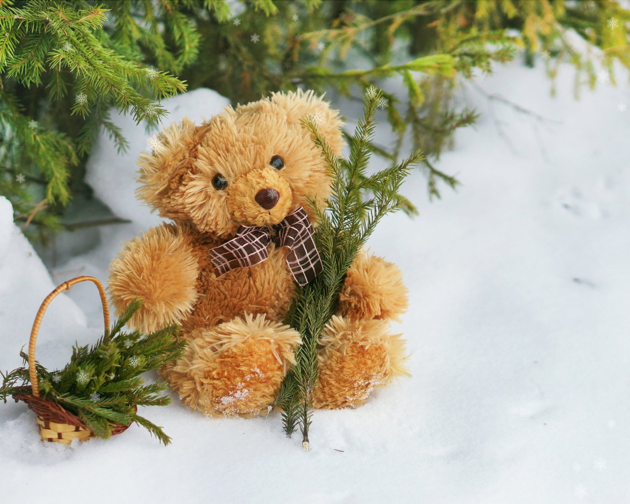 Медвежонок Тедди с веткой ели сидит на снегу