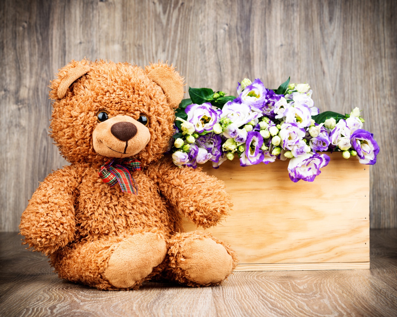 Плюшевый мишка с букетом цветов на деревянном фоне