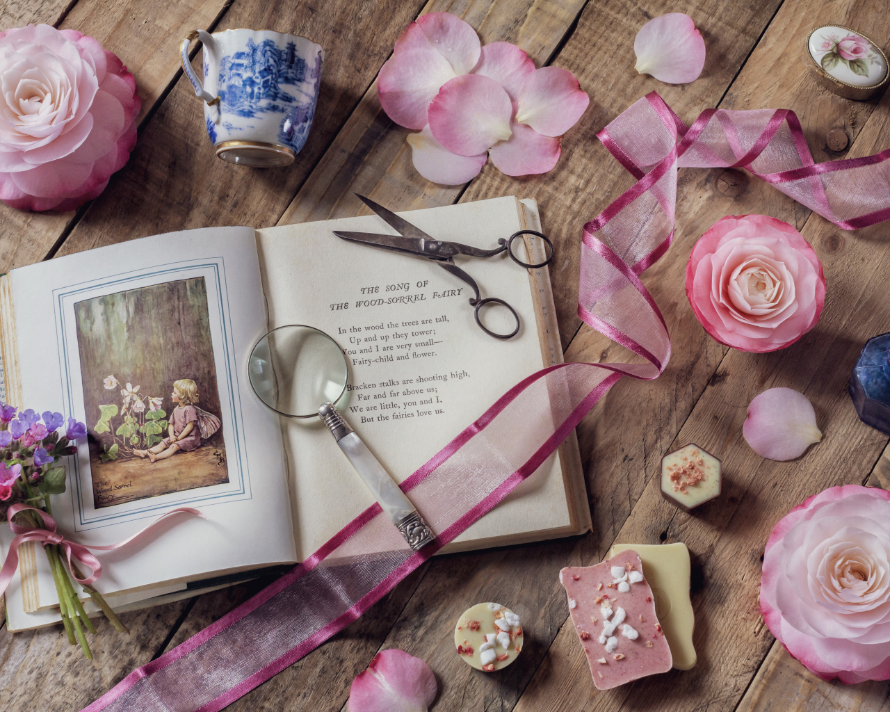 Старая книга на столе с увеличительным стеклом и искусственными цветами