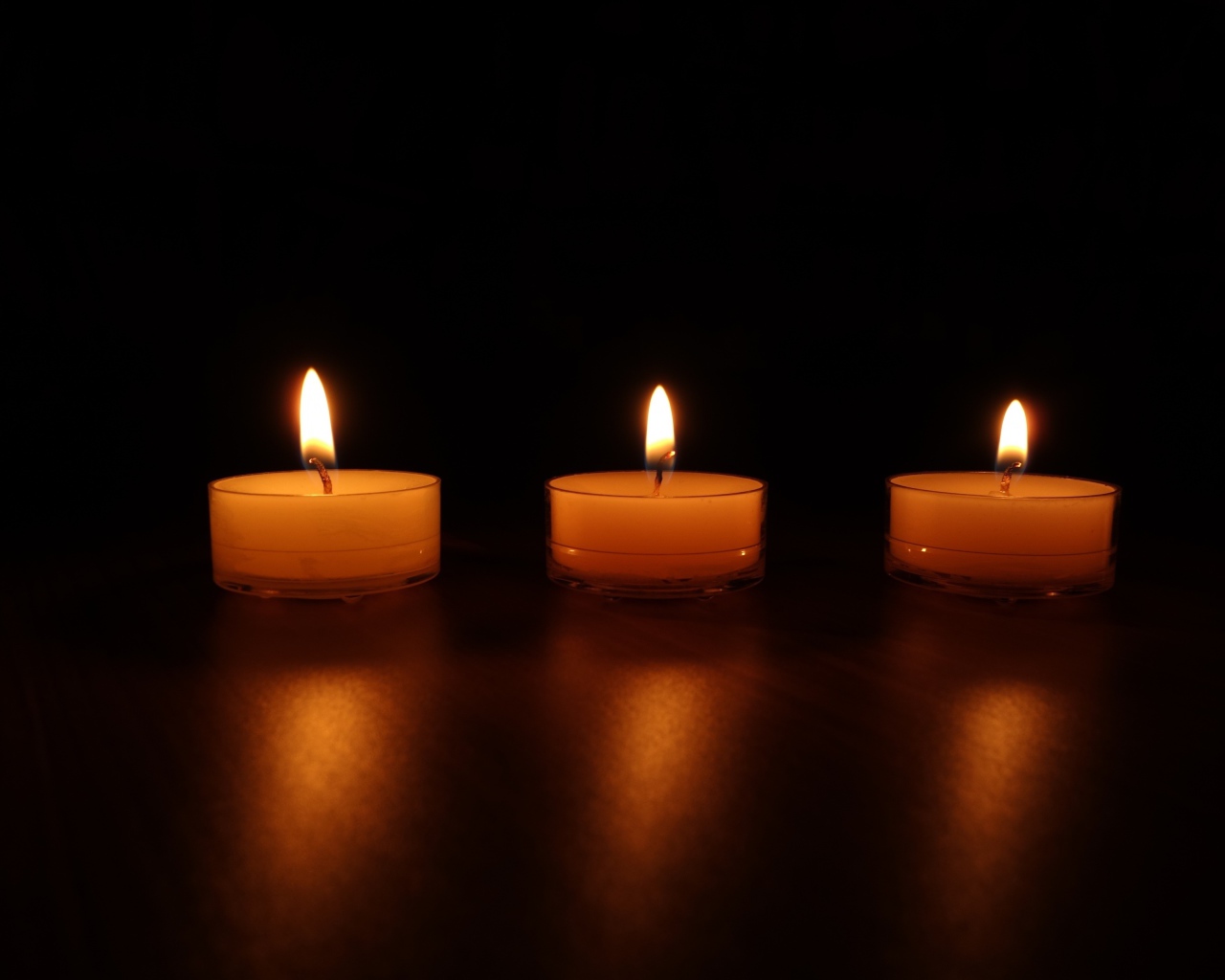 Три зажженные свечи на черном фоне