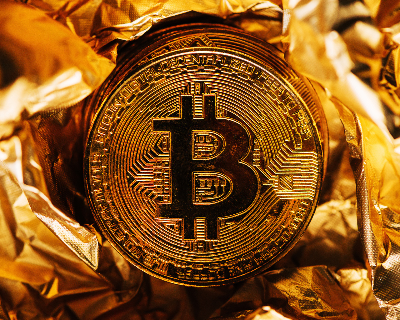 Золотая монета биткоин на фольге
