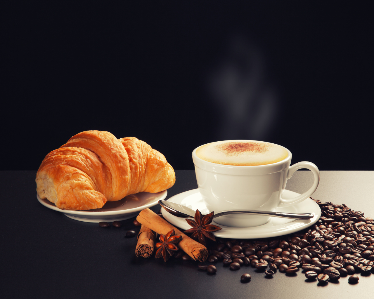 Чашка кофе на столе кофейными зернами, бадьяном, корицей  круассаном 