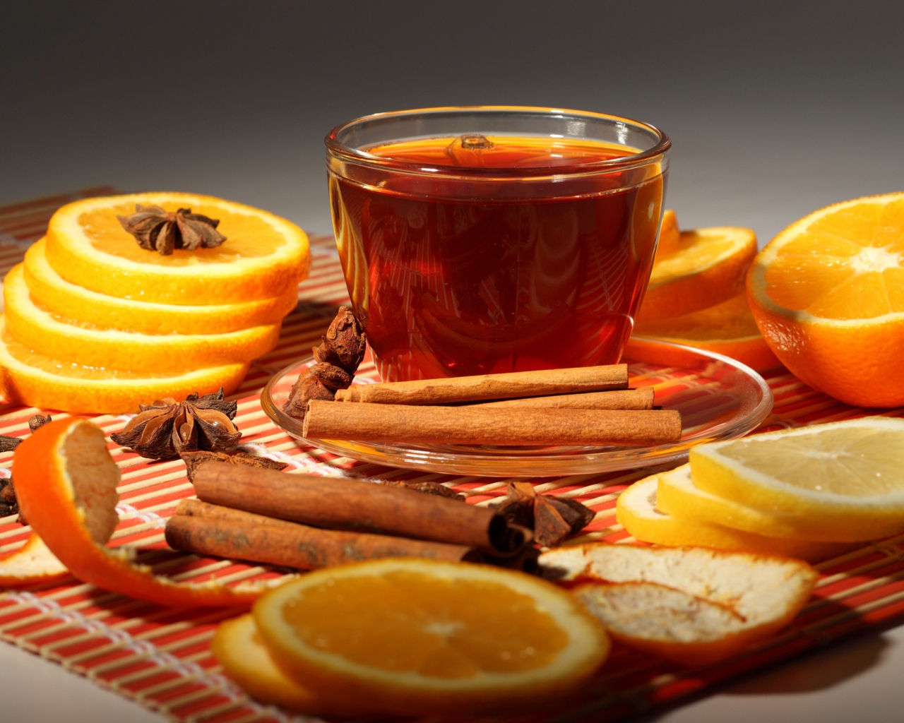 A cup of tea on the table with oranges, cinnamon and star anise
