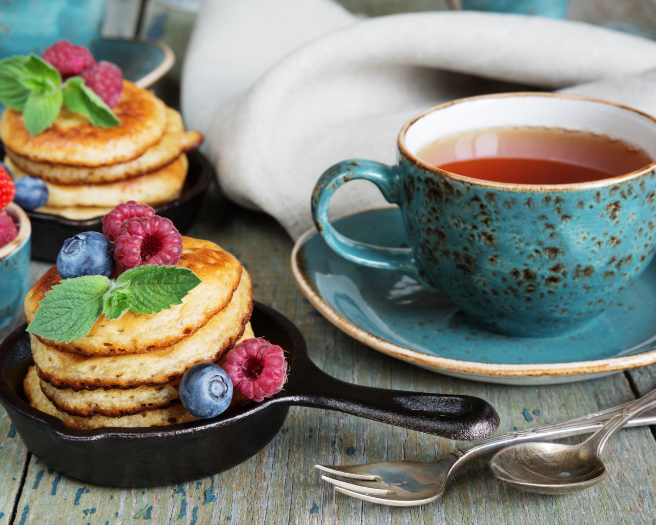 Чашка чаю с оладьями с ягодами на столе