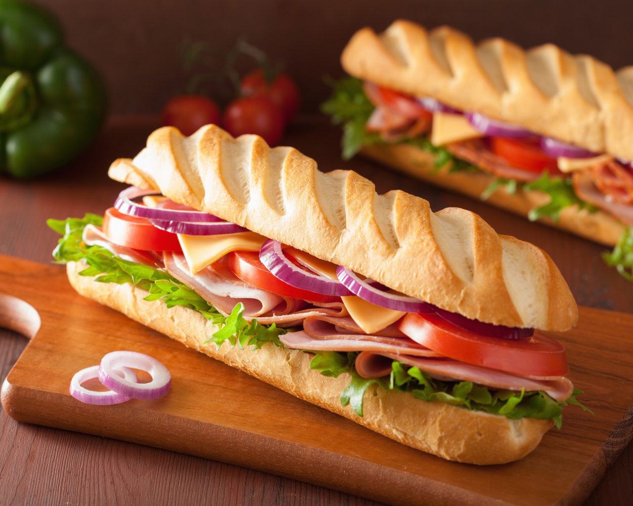 Аппетитный сэндвич с ветчиной, листьями салата, помидорами и луком