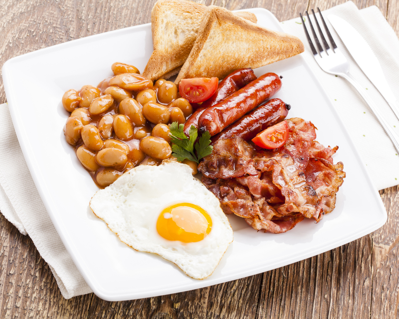 Бекон, яичница, фасоль и сосиски на тарелке к завтраку 