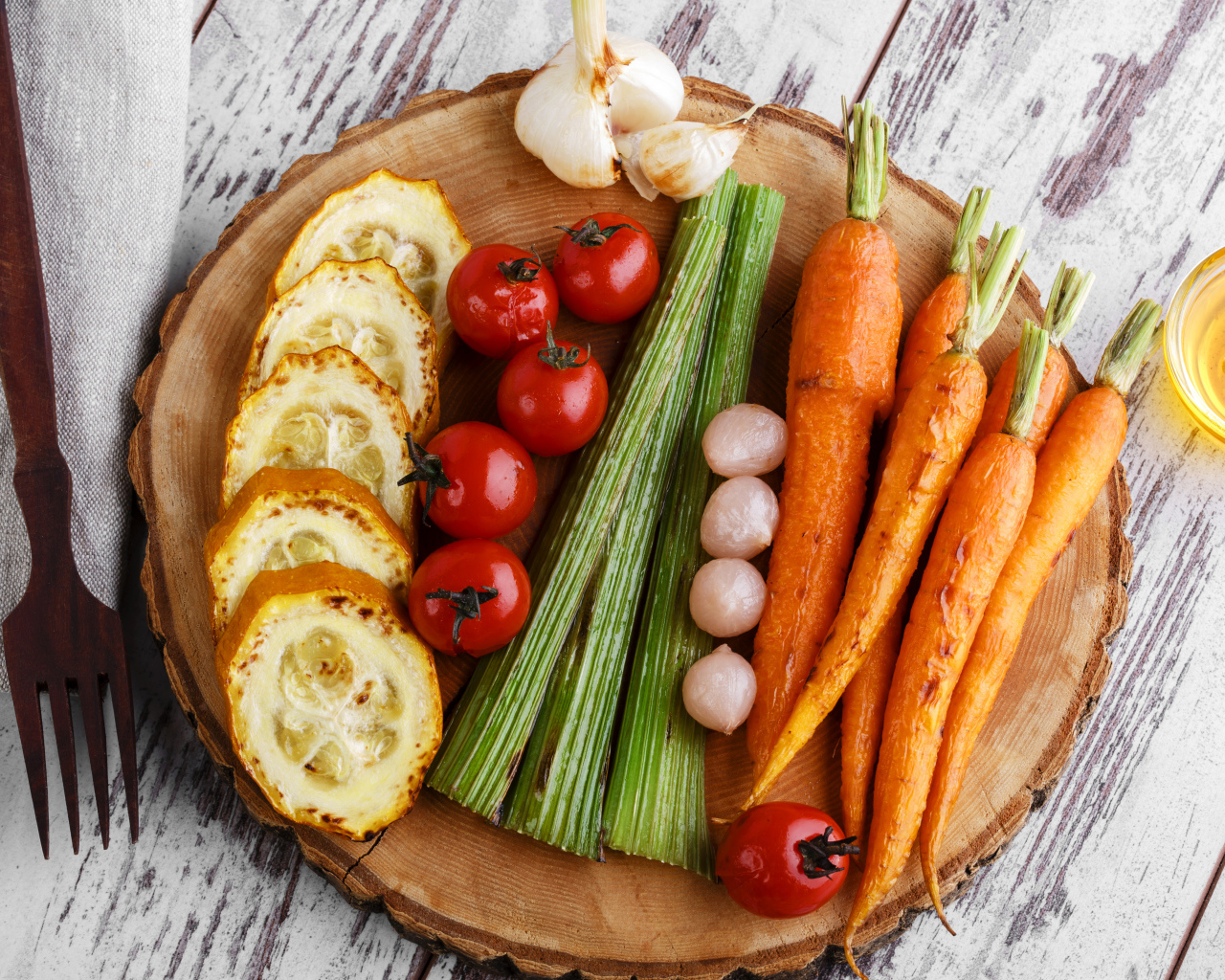 Печеные кабачки, помидоры, морковь, сельдерей и чеснок на разделочной доске
