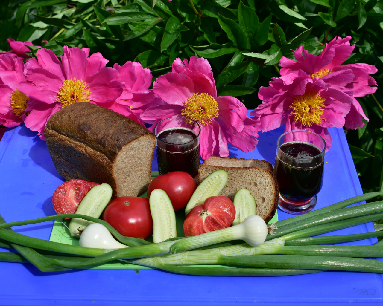 Черный хлеб, овощи и вино на фоне розовых пионов 