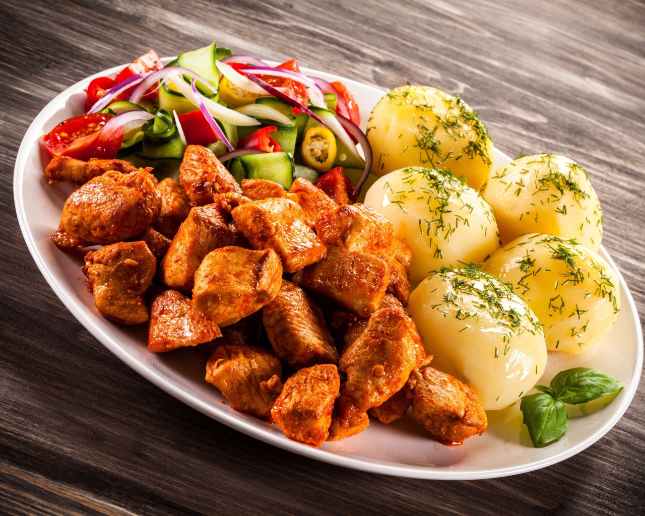 Вареный картофель с мясом и салатом на тарелке