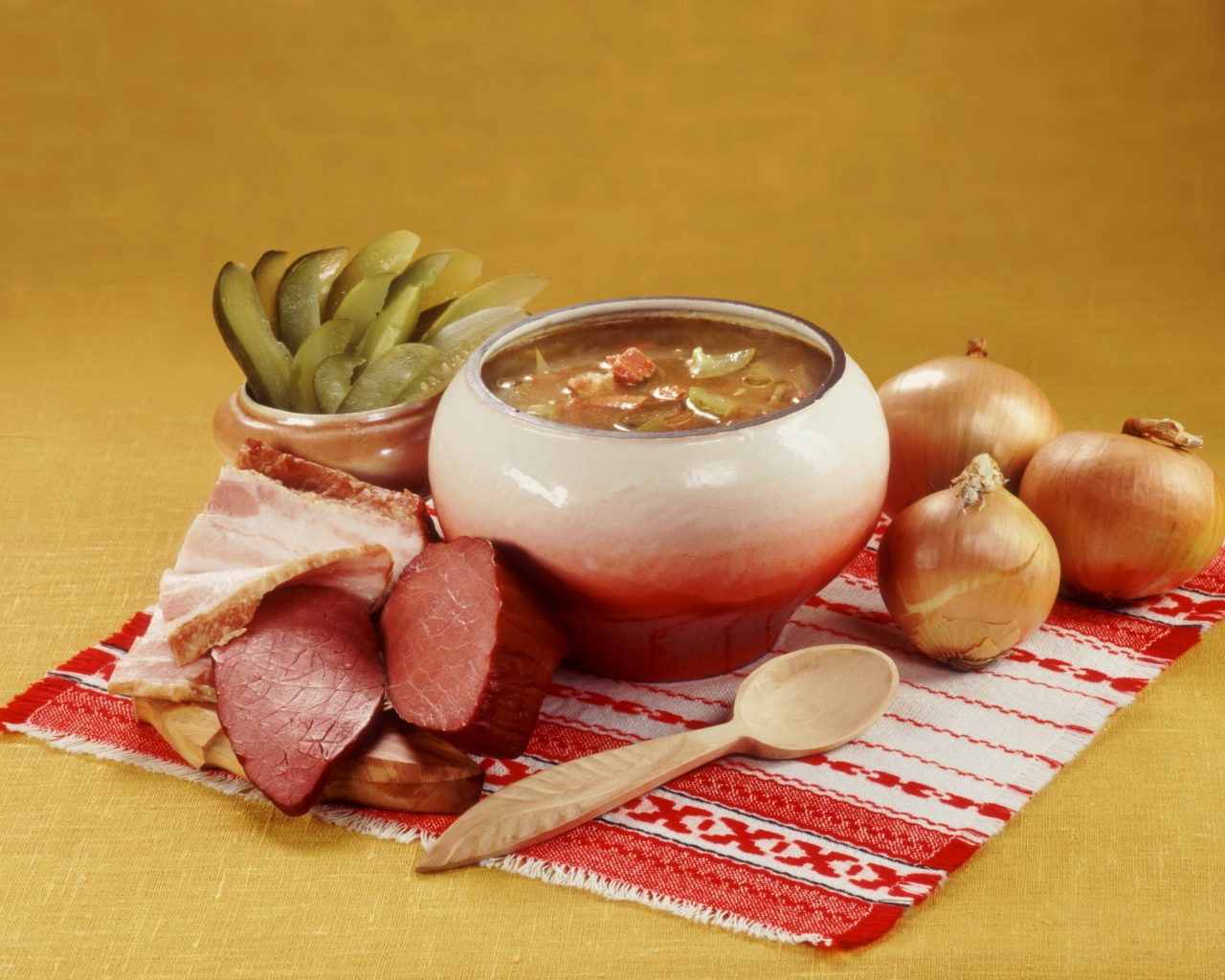 Борщ на столе с мясом, солеными огурцами и луком